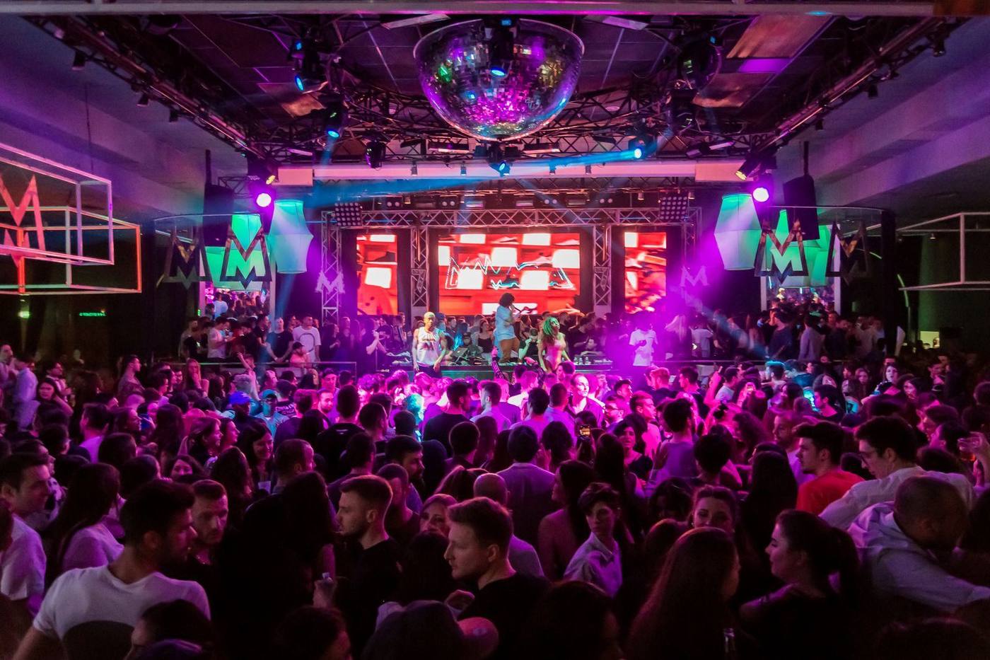 Busy nightclub dance floor under purple lighting