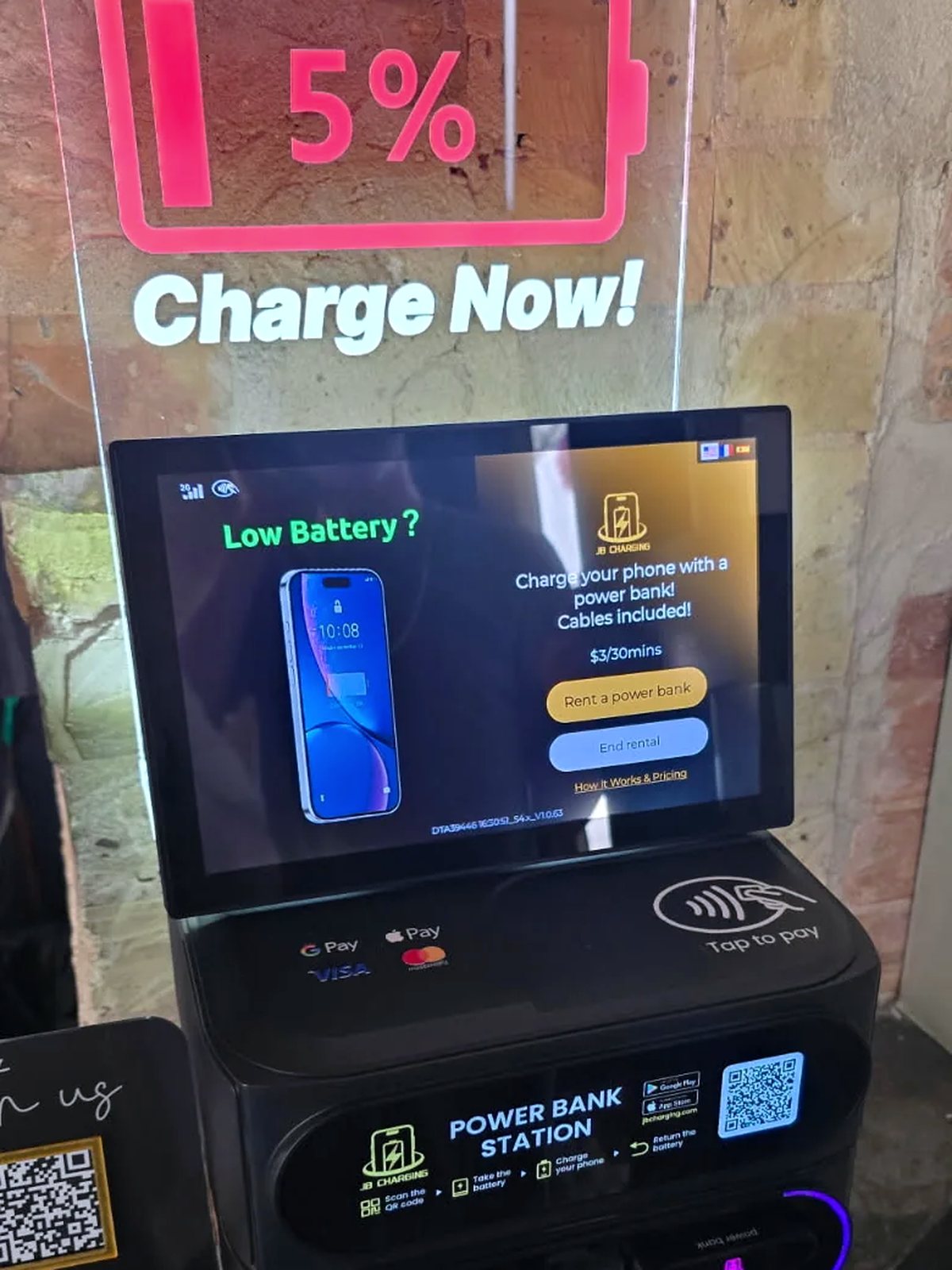 Power-bank rental station on a counter, screen on, banks ready to rent