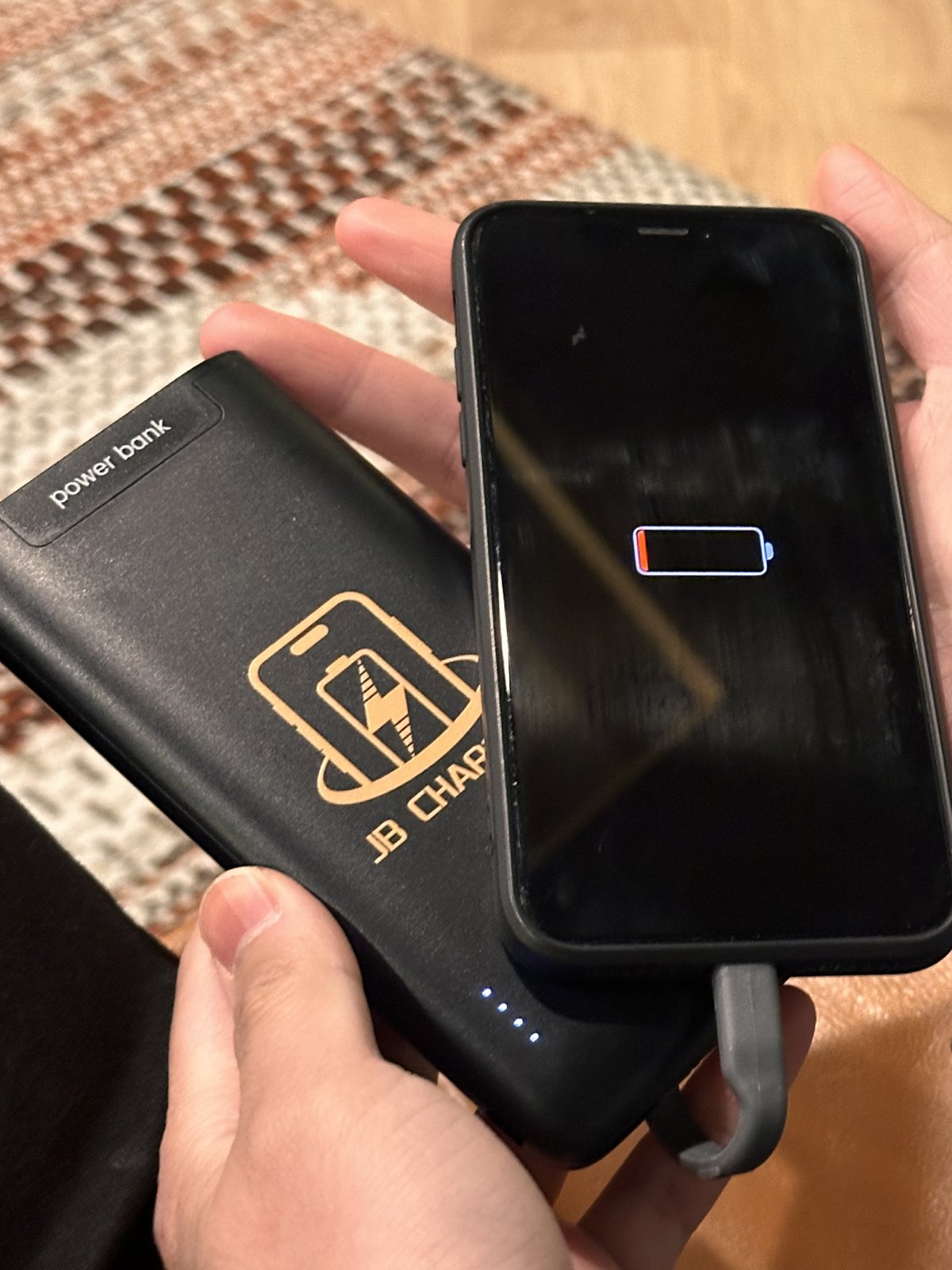 Phone plugged into a portable power bank with its cable
