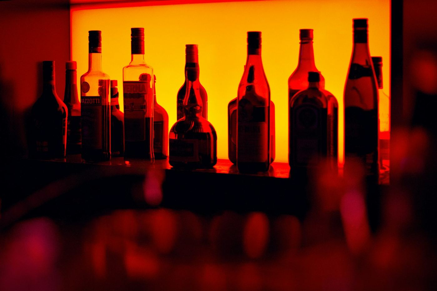 Backlit liquor bottles on a bar shelf